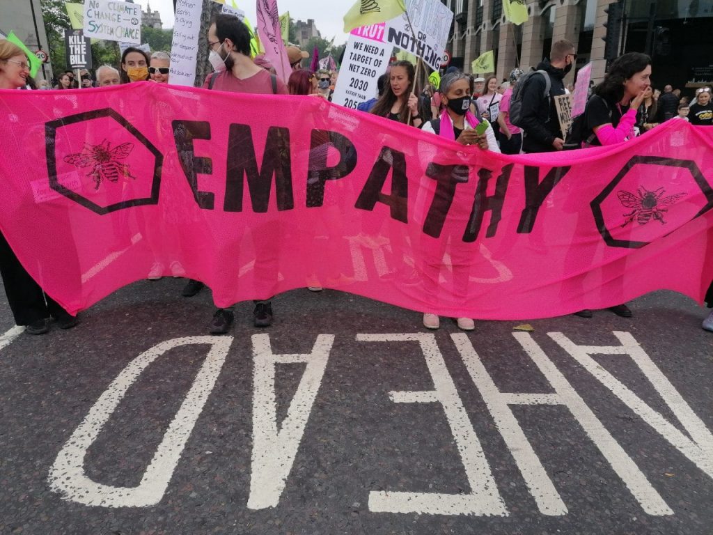 a group of people from Extinction Rebellion faith groups holding a pink banner with the word empathy printed on it.
