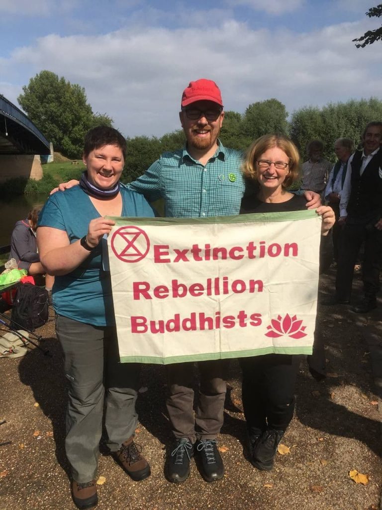 Three people holding a banner which reads Extinction Rebellion Buddhists